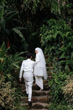 the bride and groom are walking down the stairs in their wedding attire, dressed in white