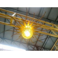 a yellow light hanging from the ceiling in a room with metal bars and beams on it