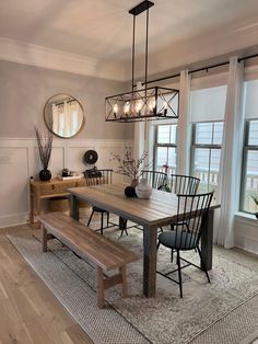 a dining room table and bench in front of two windows