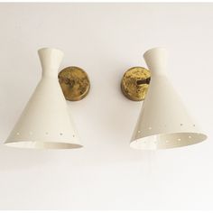 two white wall lights mounted to the side of a wall