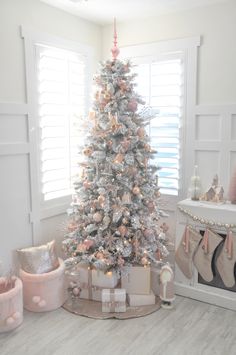 a white christmas tree with pink and gold ornaments in the corner of a living room