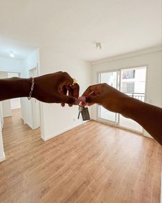 two people reaching out their hands to each other in an empty room with wood floors