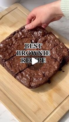 a person is cutting brownie on a wooden board with the words best brownie recipe