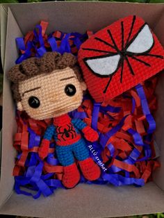 a crocheted spiderman and his friend are in a box with streamers