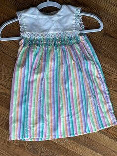 This vintage girls dress is smocked with a sailor like collar.  The closure is in the back with buttons.  The chest measurement is 26 inches and the length from shoulder seam to hem is 21.5 inches long. The stripes are orange, pink, lavender, and green with a white collar trimmed in lace. To see more of the variety of clothing we carry please visit my store at ChoiceRecycling.  We have a variety of recycled items with more to come soon. Thank you, Karmyn Vintage Smocked Summer Dress, Vintage Smocked Bodice Summer Dress, Retro Spring Dress With Smocked Bodice, Spring Vintage Smocked Dress, Spring Striped Smocked Dress With Smocked Bodice, Striped Lined Sundress, Spring Striped Smocked Dress, Striped Sundress With Lining, Striped Smocked Dress For Summer