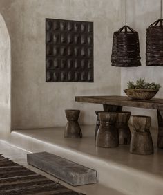 a table and some stools in a room with two lamps hanging from the ceiling