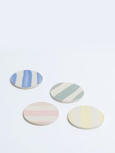 three striped coasters sitting next to each other on a white surface with blue, pink and green stripes