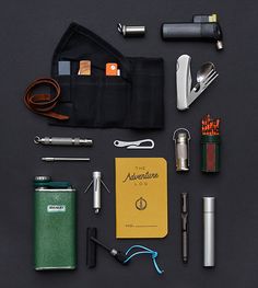 an assortment of items laid out on top of a black surface, including a notebook, pen and lighter