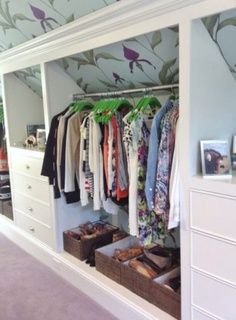 an organized closet with clothes hanging on the rails and drawers, along with other items