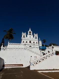 a large white building with stairs leading up to it and palm trees in the background