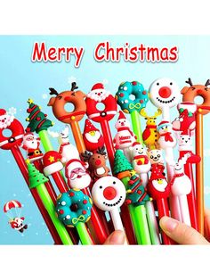 a hand is holding several christmas themed pens with santa claus and snowmen on them