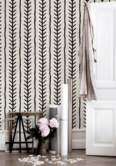 a white and black striped wallpaper next to a vase with pink flowers on it