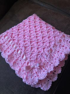 a pink crocheted blanket sitting on top of a couch