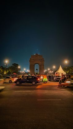 cars are parked in front of the monument at night