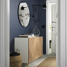 a blue room with a wooden cabinet and mirror on the wall, next to a wicker basket