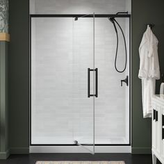 a walk in shower sitting next to a white sink and bathtub with black handles