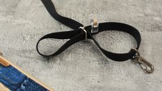 a black leash with two metal clips attached to it on top of a piece of fabric