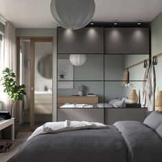 a bed sitting in a bedroom next to a wall mounted light above it's headboard