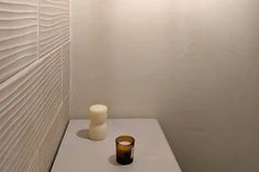 a small white table with a vase and candle on it