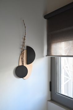 a clock mounted to the side of a white wall next to a window with blinds