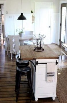 a kitchen island with stools on top of it in front of a dining room table