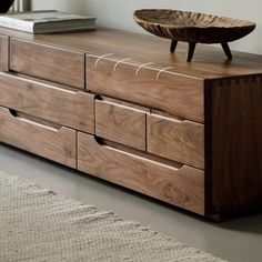 a wooden dresser with drawers and a bowl on top