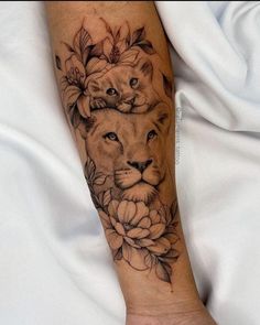 a woman's arm with a lion and flower tattoo on it