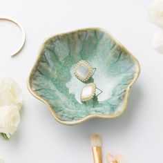 a green bowl with two rings on it next to flowers