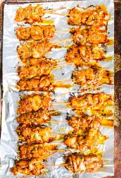 shrimp skewers on foil lined up on a baking sheet