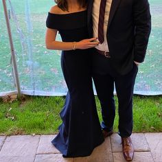 a man and woman standing next to each other in front of a tent with grass