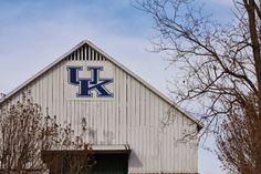 a white barn with the letter k on it's side and trees in front