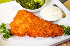 a white plate topped with fried chicken next to a bowl of broccoli and dip