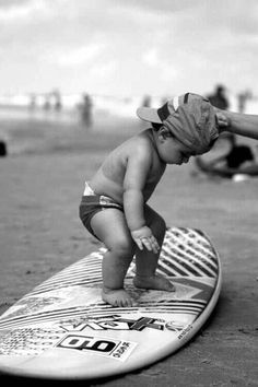 a baby standing on top of a surfboard