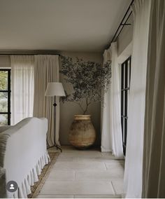 a large vase sitting in the middle of a living room next to a window with drapes