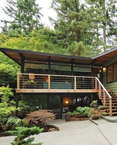 a modern house in the woods with stairs leading up to it's second story