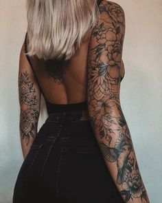 the back of a woman's body with tattoos on her arms and shoulder,