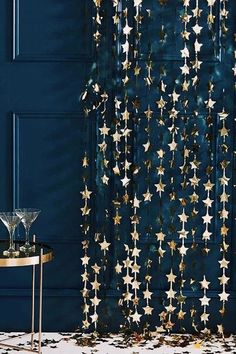 a curtain with gold stars hanging from it in front of a blue wall and table