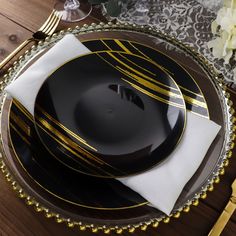 a black and gold plate with white napkins on it next to a fork and knife