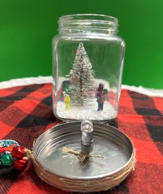 a glass jar filled with snow next to a metal tray on top of a red and black checkered table cloth