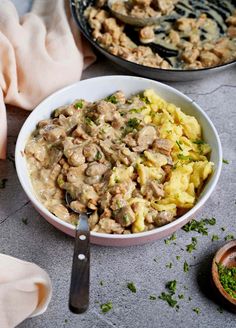 a bowl filled with meat and vegetables next to a pan full of other food items