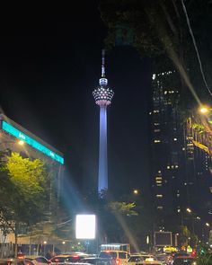 cars are driving down the street at night in front of tall buildings and skyscrapers