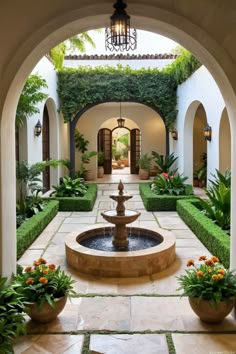 a courtyard with a fountain surrounded by greenery and potted plants on either side