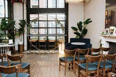 a room filled with lots of chairs and tables next to a fire place in front of a window