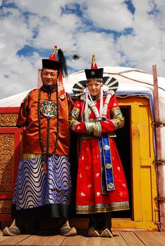 two people standing next to each other in front of a yurt with an open door