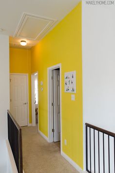 an empty hallway with yellow walls and white trim on the doors, carpeted stairs and railings