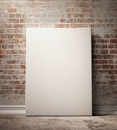 an empty white canvas in front of a brick wall with a shadow on the floor