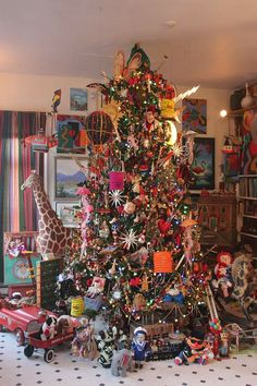 a decorated christmas tree in a living room with toys on the floor and other decorations around it