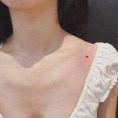 a close up of a woman's chest with small tattoos on her left shoulder