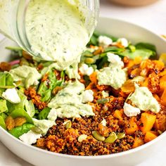 a salad with dressing being poured into it