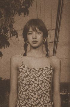 a young woman in a dress standing next to a tree with her hands on her hips